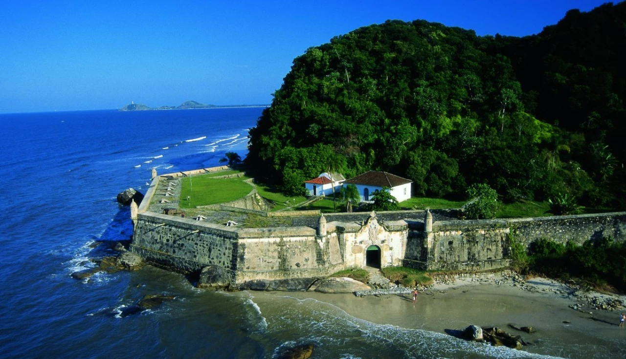 um muro de pedra com um prédio na praia