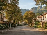 Avenida arborizada de cidade de serra com jardins floridos e montanhas ao fundo no fim da tarde